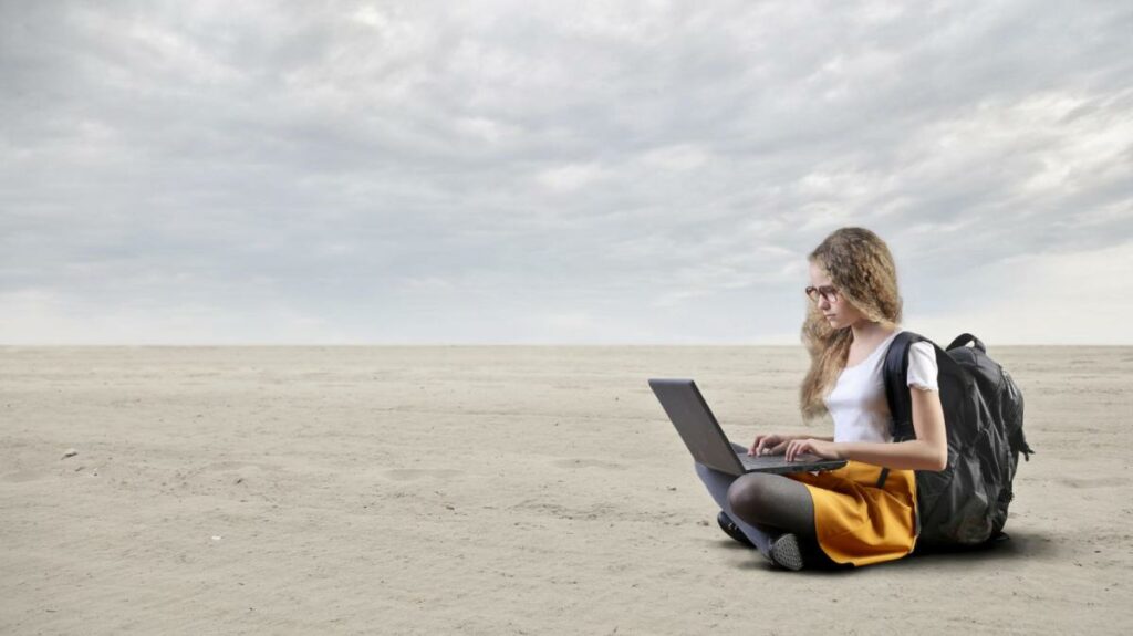 Young girl works with a pc in the desert
